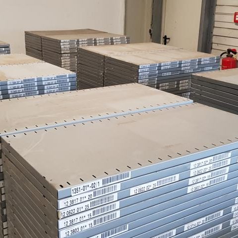 Stapelhaufen von grauen Platten in einem Lagerraum, ordentlich angeordnet.