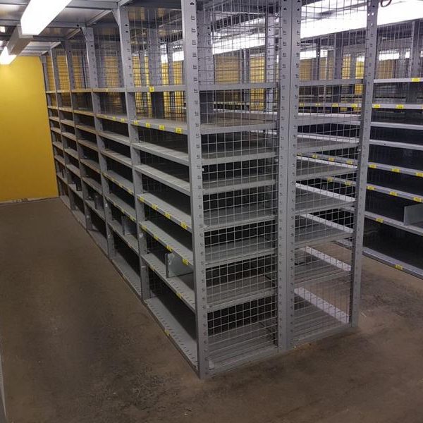 Leere Regale in einem Raum mit gelber Wand und grauem Boden.