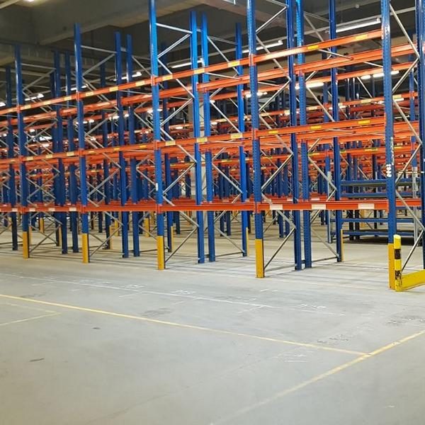 Leere Lagerregale in einem großen, hellen Raum mit grauem Boden.