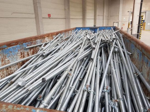 Ein Container voller metallischer Rohre und Stangen gestapelt.