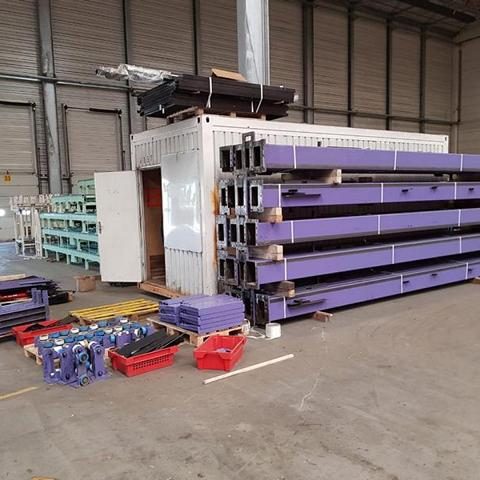 Lagerhalle mit Regalen, blauen Kisten und gefüllten roten Containern.