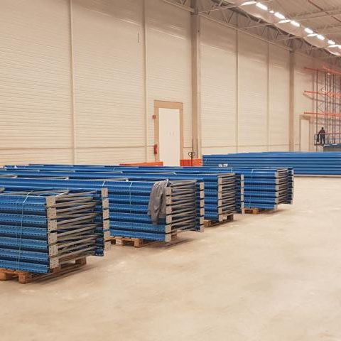 Gestapelte blaue Paletten in einem großen, leeren Lagerraum.