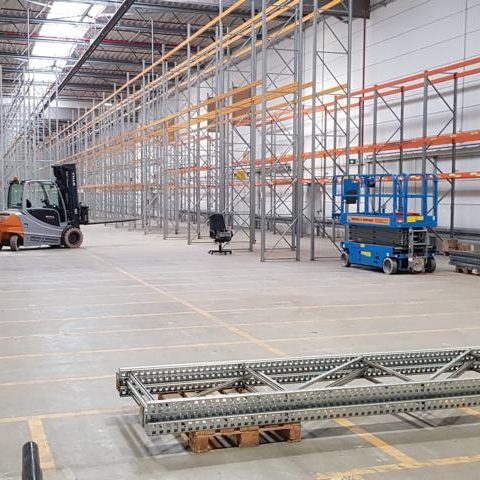 Lagerhalle mit Regalen, Gabelstapler und fahrbare Arbeitsbühne.