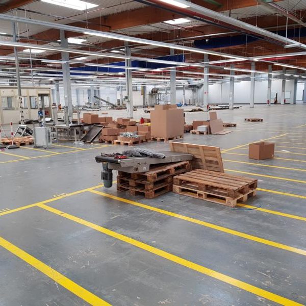 Leerer Lagerraum mit Holzpaletten und Kartons auf dem Boden.