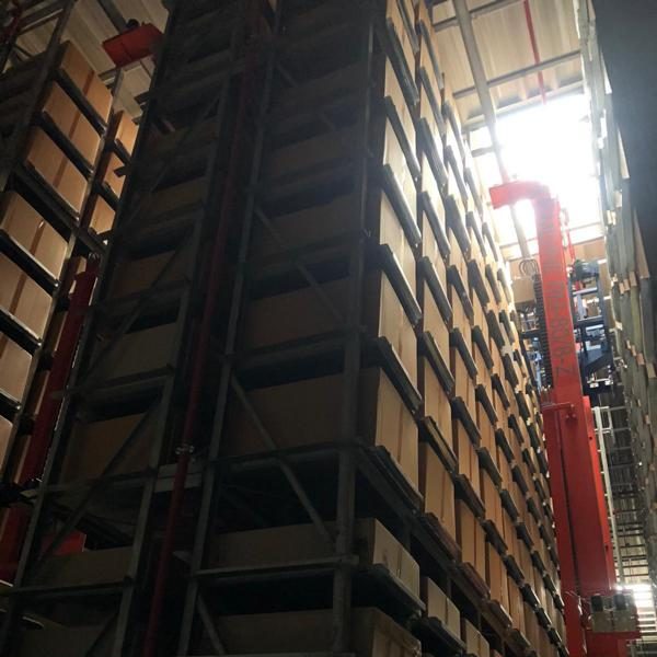 Hoher Lagerraum mit Regalen und einem Fenster, das Licht hereinlässt.