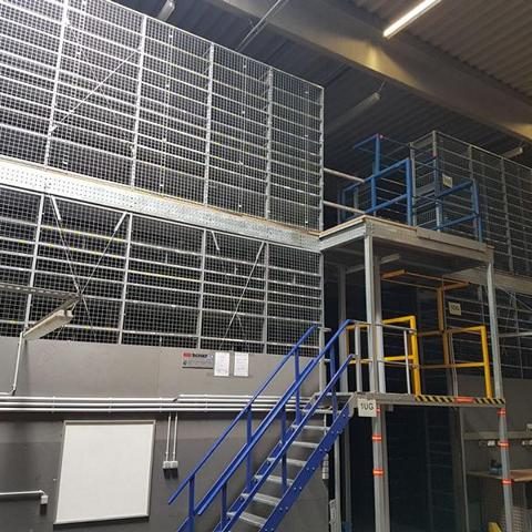 Stahlregale in einer Lagerhalle mit Treppen und offenen Läden.