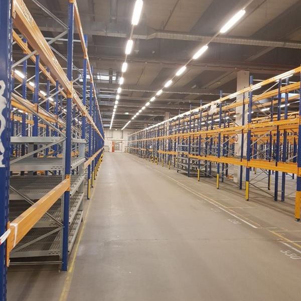 Blick auf leere Lagerregale in einem großen, beleuchteten Lagerhaus.