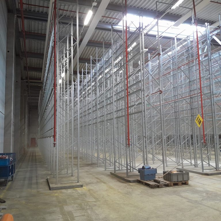 Leere Lagerhalle mit hohen Regalsystemen aus Metall.