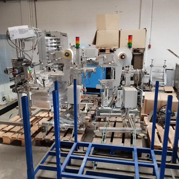 Zwei industrielle Maschinen auf blauen Gestellen in einer Lagerhalle.