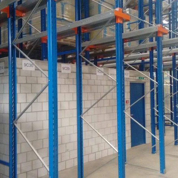 Lagersystem mit blauen Regalen und verstärkten Stützen in einem Lagerraum.