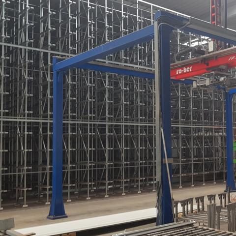 Baumaschine mit blauen Stützen und Förderband in einer Lagerhalle.