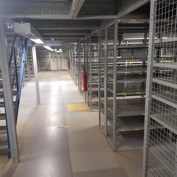 Leere, metallene Regale in einem großen Lagerraum mit Betonboden.