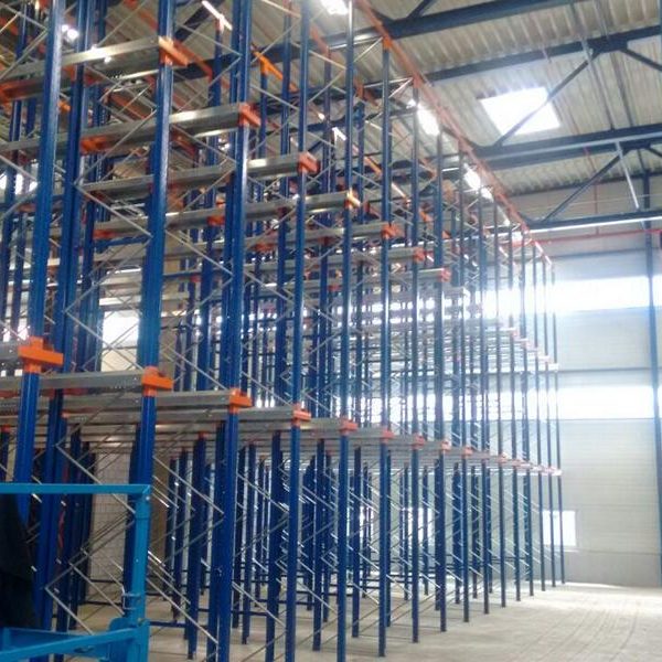 Hochregallager mit blauen und orangefarbenen Regalsystemen in einer Lagerhalle.