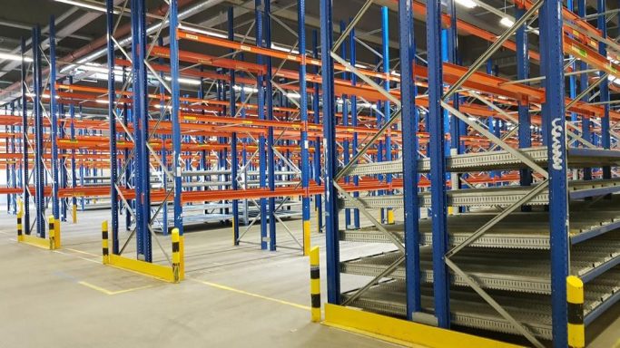 Lagerhalle mit blauen Regalen und orangefarbener Abstützung, groß und gut strukturiert.