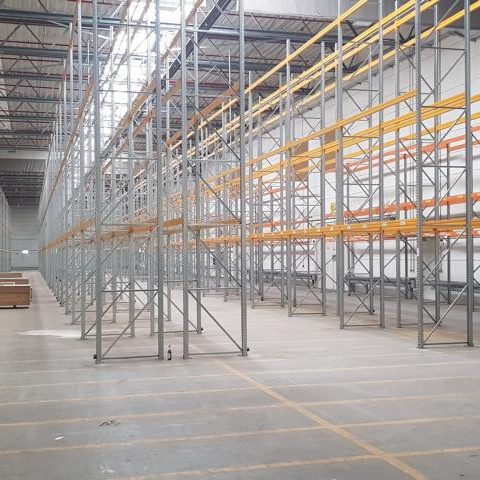 Leere Lagerhalle mit Metallregalen und orangefarbenen Regalböden.