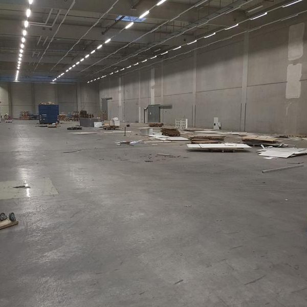 Leerer, grauer Raum mit glattem Boden und sporadischen BauMaterialien.