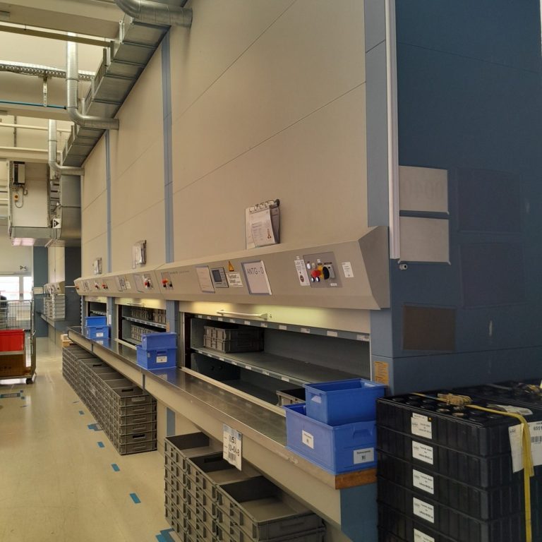 Regal mit Sortierfächern und blauen Behältern in einer Lagerhalle.