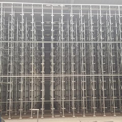 Gerüststruktur mit zahlreichen vertikalen und horizontalen Stützen in einem Baustellenbereich.