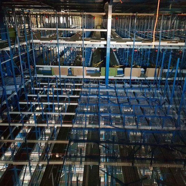 Blick auf ein Baugerüst mit blauen Metallrahmen in einer großen Lagerhalle.