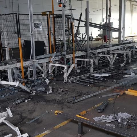 Eine unordentliche Produktionsanlage mit Trümmern und beschädigten Maschinen.