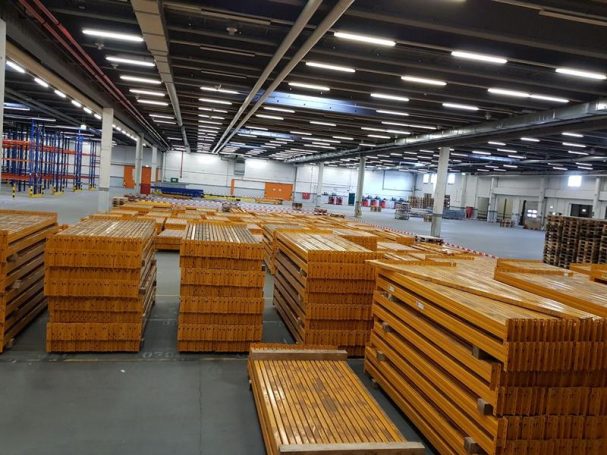 Lagerhalle mit gestapelten Holzpaneelen und regalförmigen Lagerbereichen.