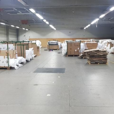 Lagerraum mit großen Kisten und Paletten, umgeben von Verpackungsmaterial.