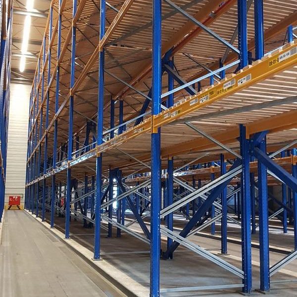 Hohe Lagerregale mit blauen Gestellen in einem großen Lagerraum.