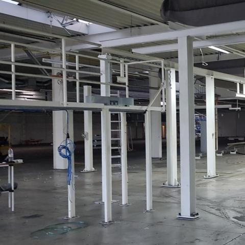 Leerer Raum mit weißen Säulen und Metallgerüst, teilweise mit Werkzeugen ausgestattet.