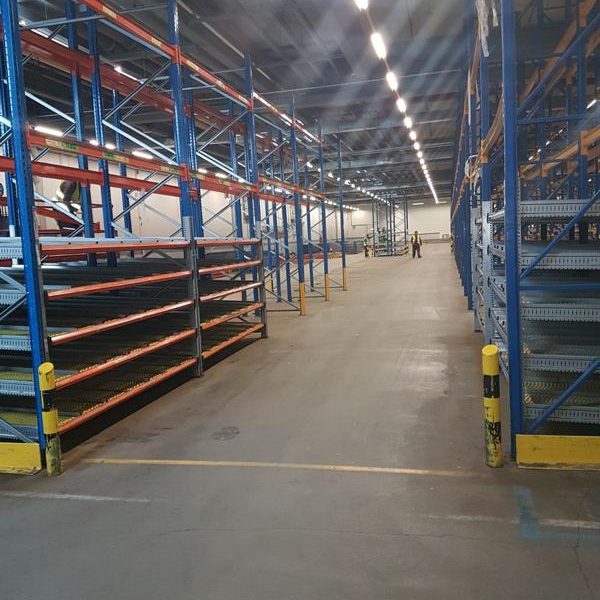 Lagerhalle mit Regalen und breitem Gang zwischen den Regalen.