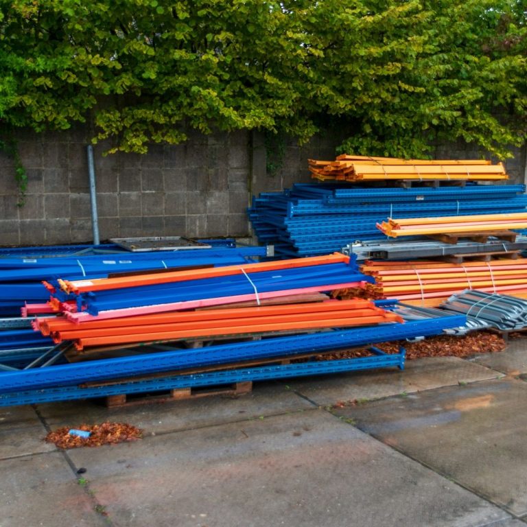 Bunte Stahlrohre in verschiedenen Längen lagern auf einem Betonboden.