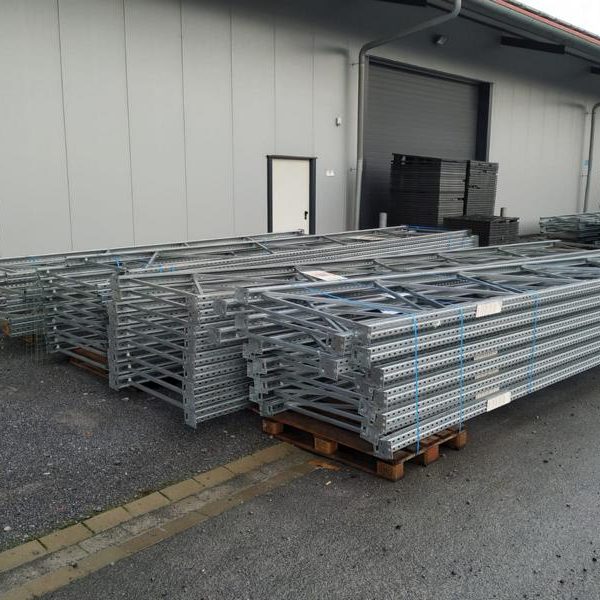 Stapeln von Verzinkungsrohren auf Holzpaletten vor einem Lagergebäude.