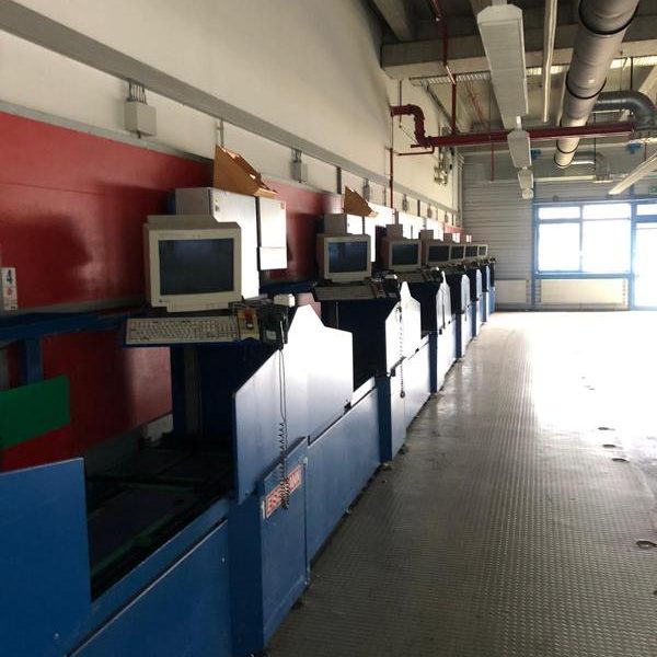 Leere Reihen von Arbeitsplätzen mit alten Computern in einem Industriegebäude.