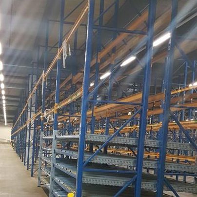 Leerer Lagerraum mit blauen Regalen und gelb markierten Bodenlinien.