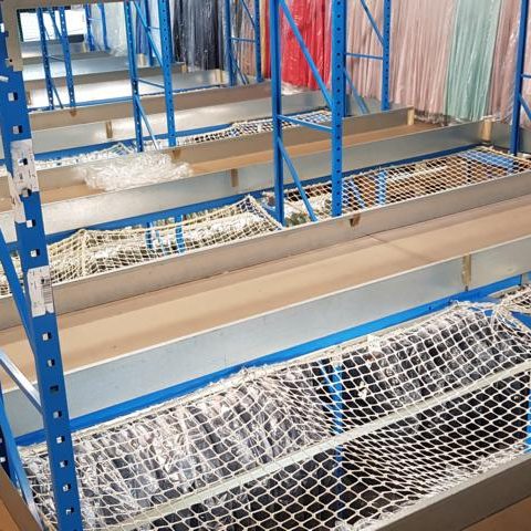 Leere Regale in einem Lager mit blauen Gestellen und weißen Netzen.