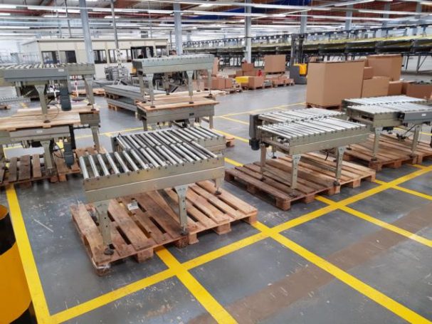 Mehrere Metallgestelle auf Holzpaletten in einer Lagerhalle.