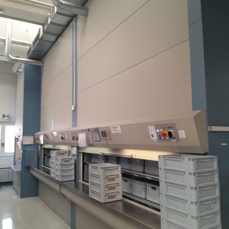 Moderne Küchenzeile mit Regalen und Kontrollen an der Wand, leere Behälter darunter.