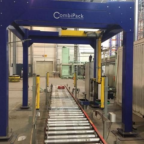 Blauer Verpackungsapparat mit Förderband in einer Lagerhalle.