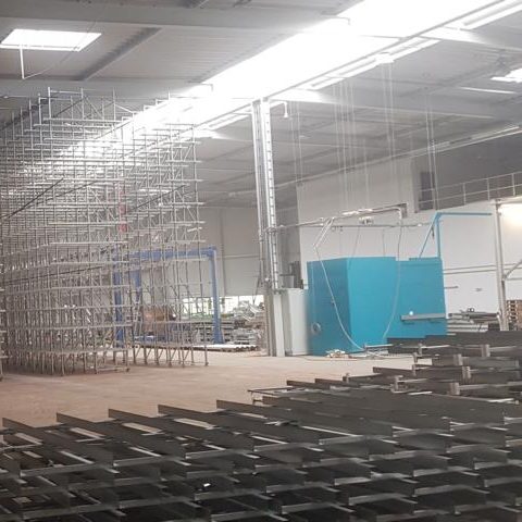 Großer Raum mit Metallregalen und Stuhlreihen auf dem Boden. Beleuchtung oben.