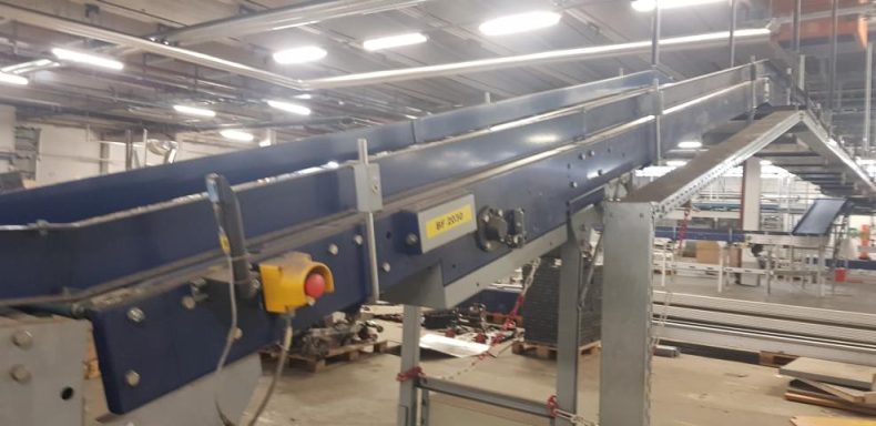 Transportband in einer Lagerhalle, verbunden mit verschiedenen Maschinen.