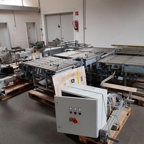 Zusammengebaute Maschinen in einer Lagerhalle, teilweise abgedeckt und ungenutzt.