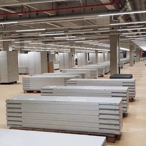 Lagerhalle mit gestapelten weißen Platten auf Paletten in geordneter Anordnung.