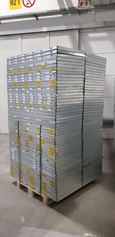 Ein hoher Stapel aus silbernen Metallplatten auf einer Holzpalette.