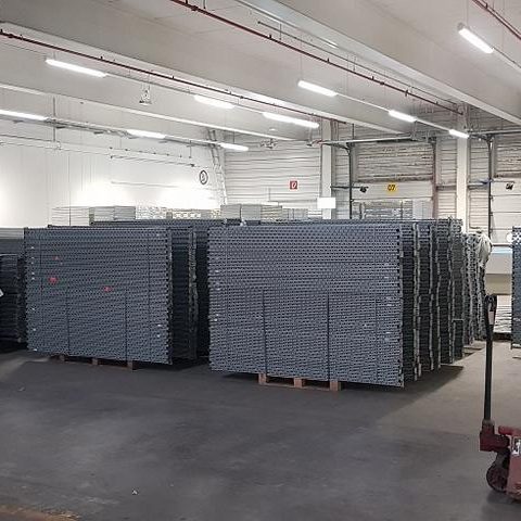 Lagerhalle mit gestapelten grauen Regalen auf einem Betonboden.