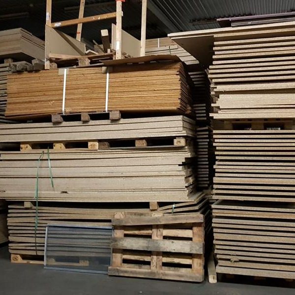 Verschiedene Holzplatten und -tafeln auf Paletten in einem Lager.