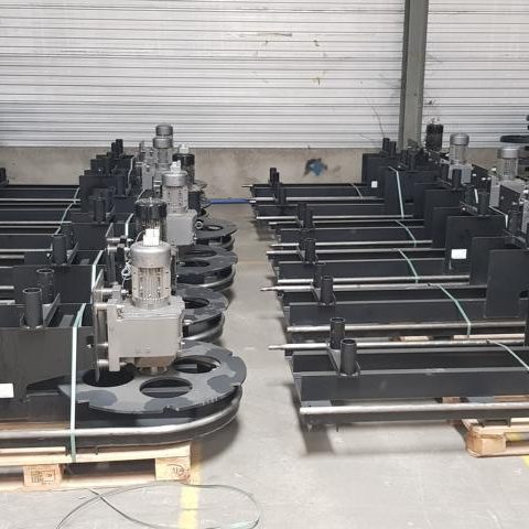 Mehrere Maschinenkomponenten in einer lagerähnlichen Umgebung auf Paletten angeordnet.