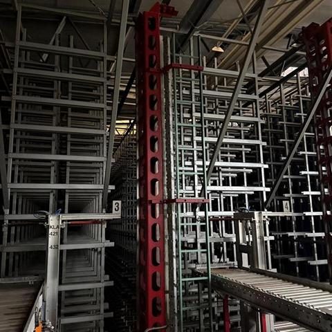 Regalstruktur mit metallenen Regalen und einem Förderband in einem Lagerraum.