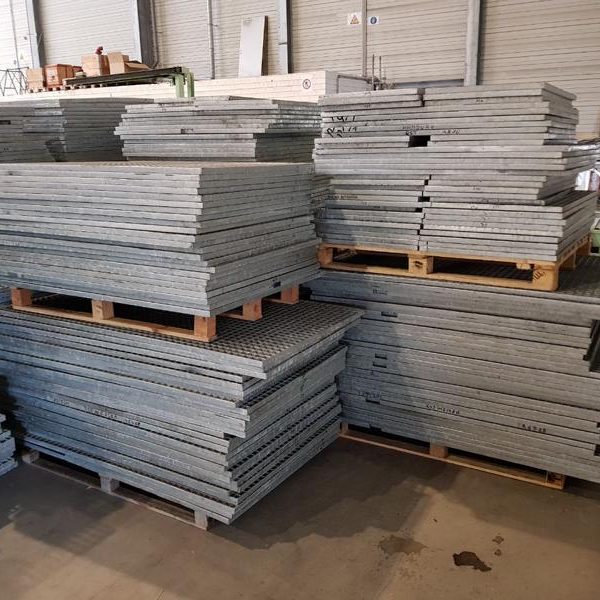 Stapeln von grauen Blechen auf Holzpaletten in einem Lager.