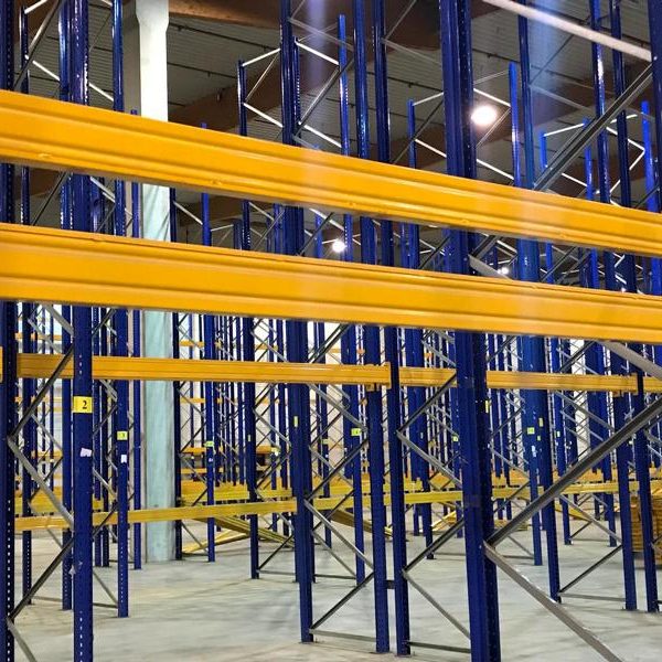Lagerregale mit blauen Rahmen und gelben Ablagen in einem großen Raum.