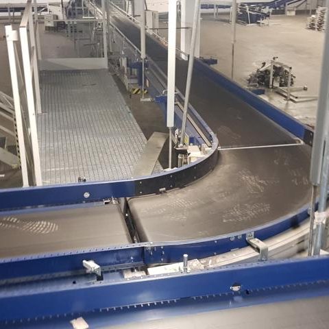 Förderband mit Kurven in einer modernen Lagerhalle.