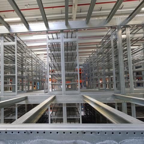 Produktionsmaschine in einer Fabrikhalle, ausgestattet mit mehreren Arbeitsbereichen.